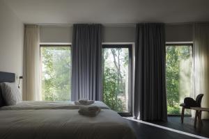a bedroom with a bed and two large windows at Domein Polderwind in Zuienkerke