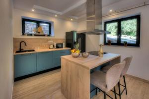 a kitchen with blue cabinets and a table with chairs at Villa VlaMar - new luxury house in Goveđari