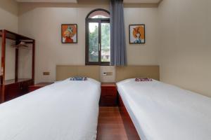 two beds in a room with a window at Kaibu Courtyard Superior Apartment, Changjiang Cable Car Nanbin Road, Chongqing in Chongqing