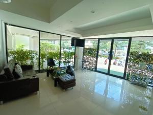 a living room with a couch and a chair and windows at Tisa Hotel Udonthani in Udon Thani