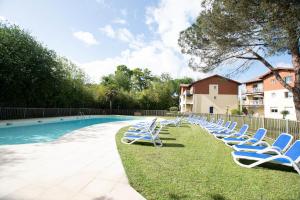 a row of lounge chairs sitting next to a swimming pool at Appartement 29 Plages à pied in Capbreton