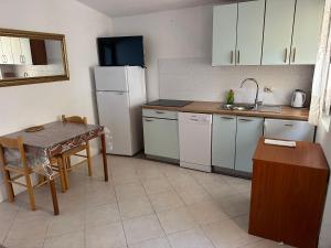 a kitchen with a table and a white refrigerator at Apartment 2 (+1) in Ljubač