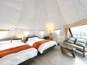 a bedroom with two beds and a couch at 奏の森リゾート　フォレストグランピング in Ito