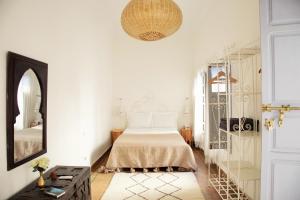 a white bedroom with a bed and a mirror at Riad Dar Wildeve in Marrakech