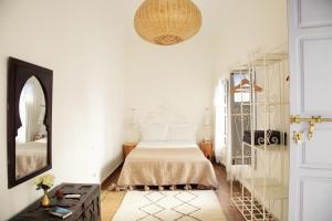 a white bedroom with a bed and a mirror at Riad Dar Wildeve in Marrakesh