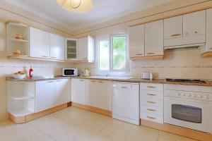 a white kitchen with white cabinets and a window at Villa La Pinta in Santanyi