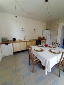 a kitchen with a table with chairs and a white table cloth at Vacation Rental in Ambleville +21 photos