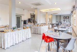 a restaurant with white tables and chairs and tablesktop at Albergo Aquila in Rimini