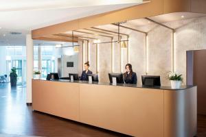 奥伯丁NH酒店慕尼黑机场店的两名妇女坐在办公室的接待台