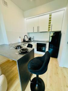 a kitchen with a black chair next to a counter at H ApartStudio Targowa 4 in Ełk