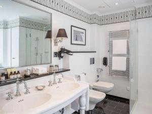 a white bathroom with a sink and a toilet at Fairmont Hotel Vier Jahreszeiten in Hamburg
