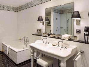 a white bathroom with a sink and a bath tub at Fairmont Hotel Vier Jahreszeiten in Hamburg