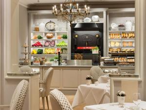 a restaurant with a counter with tables and chairs at Fairmont Hotel Vier Jahreszeiten in Hamburg