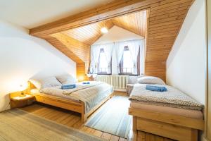 two beds in a room with wooden ceilings at Penzión Šafran Stratená in Stratená