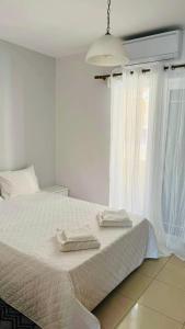 a bedroom with a white bed with two towels on it at AQUALIA Apartment 2 in Karpathos Town