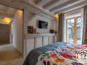 ein Schlafzimmer mit einem Bett und einem Fernseher an der Wand in der Unterkunft Chambre d'hôtes avec piscine et petit-déjeuner proche d'Angers - FR-1-622-84 in La Rochefoulques
