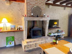ein Wohnzimmer mit Kamin, Fernseher und Tisch in der Unterkunft Gîte tout confort avec grand jardin, cheminée, clim et WIFI, proche châteaux de la Loire et ZooParc de Beauval - FR-1-491-400 in Le Controis En Sologne