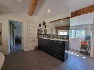 a large kitchen with a black counter and sink at Mas Montet Chez Raphael in La Valette