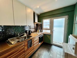 a kitchen with green walls and wooden cabinets and a sink at L'Havre luxueux de la cité Ardente - Central in Liège +23 photos