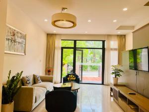 Royal Lotus Hạ Long Resort & Villas في ها لونغ: غرفة معيشة مع أريكة وتلفزيون