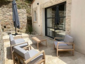 a patio with chairs and an umbrella and a table at Le charme des bois in Alès