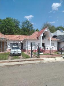 a white house with a fence and a car in it at Casa Elisei in Asău