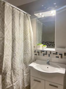 エルミオニにあるOikonomou Villasの洗面台とシャワーカーテン付きのバスルーム