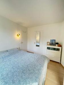 a white bedroom with a blue bed and a cabinet at Logement entier proche de Paris in Croissy-sur-Seine