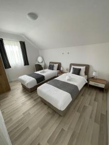 two beds in a large room with wooden floors at Apartman Naturalis flumen in Otočac