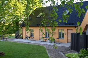 a yellow house with a black roof and a yard at Allé på Österlen in Kivik