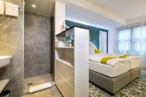 a small bathroom with a bed and a sink at ARCOTEL Donauzentrum Wien in Vienna