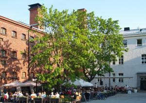 a group of people sitting at tables under a tree at Home Hotel Katajanokka in Helsinki