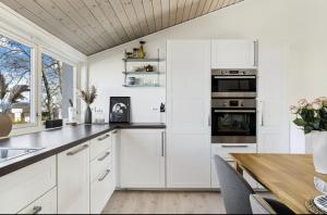 a kitchen with white cabinets and a wooden table at Rekkehus sentralt i Stavanger - nære ONS messen in Stavanger