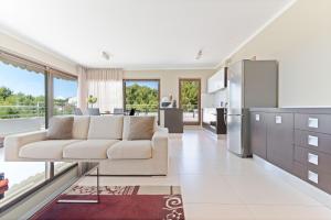 a living room with a white couch and a kitchen at The Residence Aparthotel in Podstrana
