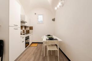 a white kitchen with a white table and chairs at The First Porta Soprana Prione in Genoa