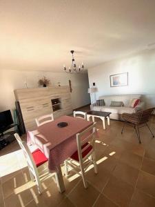 Una sala de estar con una mesa y sillas y un sofá. en Appartement vue mer B21, parking privé, en Saintes-Maries-de-la-Mer