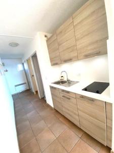Una cocina con gabinetes de madera y piso de baldosas. en Appartement vue mer B21, parking privé, en Saintes-Maries-de-la-Mer