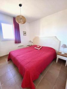 Un dormitorio con una cama roja con una manta roja. en Appartement vue mer B21, parking privé, en Saintes-Maries-de-la-Mer