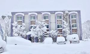 a snow covered building with cars parked in front of it at Hakuba King Hotel in Hakuba
