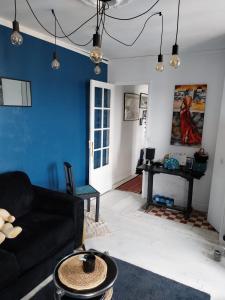 a living room with a black couch and a blue wall at Beau studio à Fontenay sous bois in Fontenay-sous-Bois