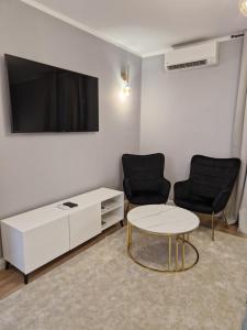 een woonkamer met 2 stoelen, een tafel en een tv bij Luxury Apartment Paper in Zagreb