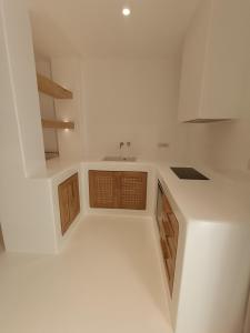 a white kitchen with a sink and wooden cabinets at Yialos Ios Hotel in Ios Chora