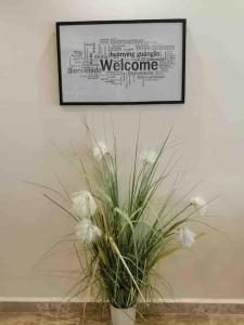a plant in a white vase on a wall with a picture at Spacious Apart, 2-min to beach & Old Souk in Jbeil +11 photos