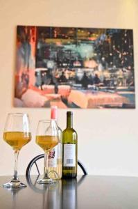 two glasses of wine on a table with a painting at Spacious Apart, 2-min to beach & Old Souk in Jbeil