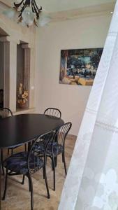 a black dining room table with chairs and a painting at Spacious Apart, 2-min to beach & Old Souk in Jbeil