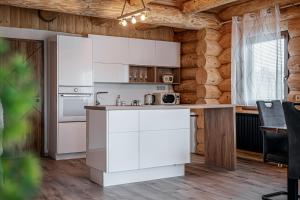a kitchen with white cabinets in a wooden room at Zrub Šumiac in Šumiac