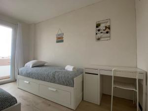 Un dormitorio blanco con una cama y un escritorio. en Joli T4 avec balcon, place de parking - Oradou, en Clermont-Ferrand