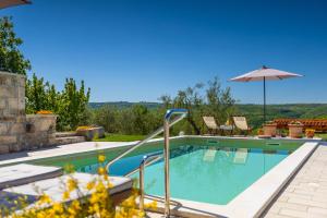 una piscina con sombrilla y sillas en Beautiful Villa Cartolina with pool in Buje, en Krasica