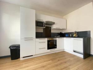 Una cocina con gabinetes blancos y electrodomésticos negros. en Joli T4 avec balcon, place de parking - Oradou, en Clermont-Ferrand