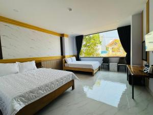 ein Schlafzimmer mit zwei Betten und einem Schreibtisch und einem Fenster in der Unterkunft Khách Sạn Metro Ban Mê in Buon Ma Thuot